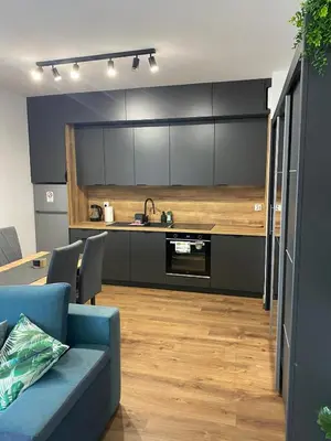 a kitchen with black cabinets and a blue couch in a room at EM Room in Kraków