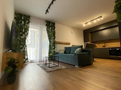 a living room with a blue couch and a kitchen at EM Room in Kraków