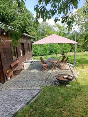 a patio with an umbrella and a table and chairs at Drewniany domek na wynajem Beskid Wyspowy in Limanowa