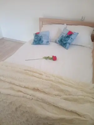 a white bed with blue pillows and a rose on it at Zaciszny zakątek pod Różą in Skawinki