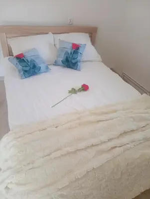 a white bed with two pillows and a rose on it at Zaciszny zakątek pod Różą in Skawinki