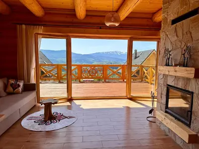 a living room with a fireplace and a large window at Sielska Chata Beskidy in Zawoja