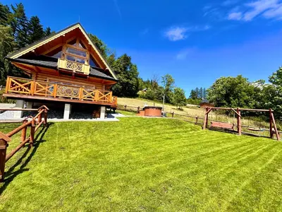 a log cabin with a grassy field in front of it at Sielska Chata Beskidy in Zawoja