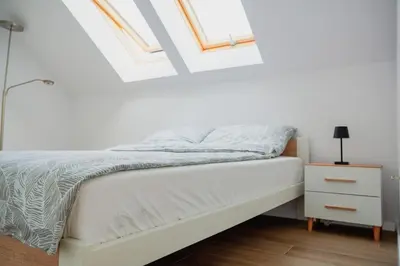 a bedroom with a white bed with a nightstand and skylights at Dom obok lasu pod Krakowem in Zabierzów