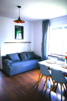 a living room with a blue couch and a table at Srokówka Resort in Dąbrówka