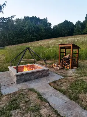 a fire pit in a field with a wooden structure at Srokówka Resort in Dąbrówka