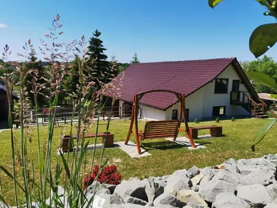 a park with a bench and a house at Srokówka Resort in Dąbrówka