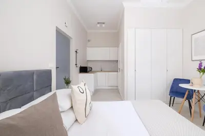 a white bedroom with a large bed and a kitchen at Studio Apartment With Terrace -Starowślna 43 in Kraków