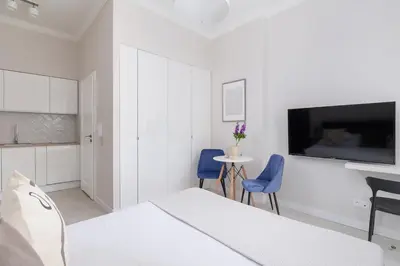 a white room with a bed and two blue chairs at Studio Apartment With Terrace -Starowślna 43 in Kraków