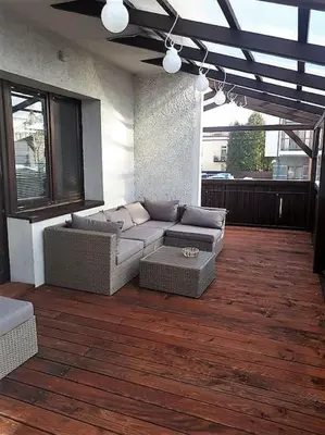 a patio with a couch and a table on a wooden floor at Apartament Roztoki 4a in Rabka-Zdroj