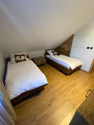 two beds in a room with wooden floors at Zander Village Zator in Palczowice