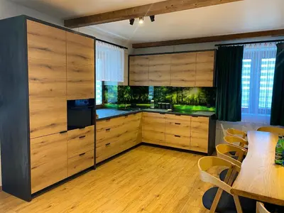 a kitchen with wooden cabinets and a table with chairs at Zander Village Zator in Palczowice