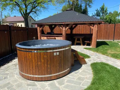 a wooden hot tub in a yard with a gazebo at Zander Village Zator in Palczowice