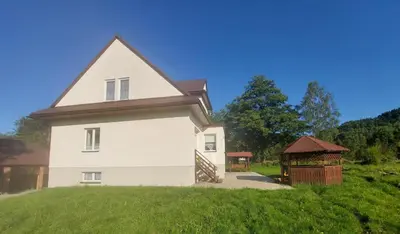 a white house with a gazebo in a yard at Apartament u Majki in Bystra