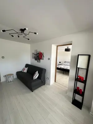 a living room with a black couch and a mirror at Apartament u Majki in Bystra