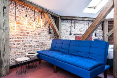 a blue couch in a room with a brick wall at 1-bedroom apartment with an AC - Dietla 51 street in Kraków