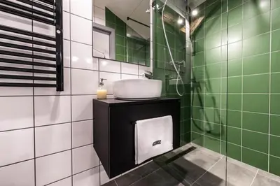 a bathroom with a sink and green and white tiles at Studio with an AC - Dietla 51 street in Kraków