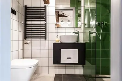 a bathroom with a green and white tiled wall at Studio with an AC - Dietla 51 street in Kraków