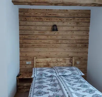 a bed in a bedroom with a wooden wall at Dom pod Turbaczem in Nowy Targ