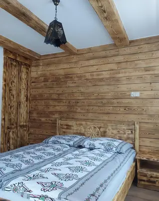 a bedroom with a wooden wall with a bed at Dom pod Turbaczem in Nowy Targ