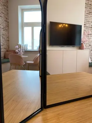 a mirror reflecting a living room with a table and a tv at Royal Rose Apartment - Old Town Kraków in Kraków