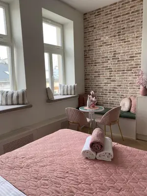 a bedroom with a pink bed and a brick wall at Royal Rose Apartment - Old Town Kraków in Kraków