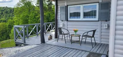 a porch with two chairs and a table with flowers on it at Domek na Brzeziu in Limanowa
