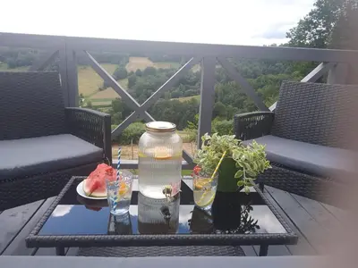 a table with a vase and glasses on a balcony at Domek na Brzeziu in Limanowa