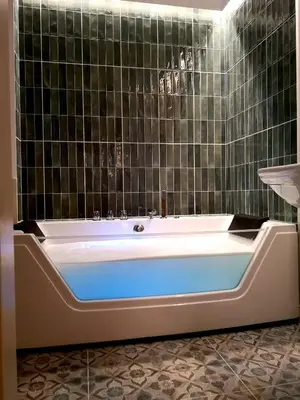a bath tub in a bathroom with black tiles at WANNA SPA na Starym Mieście in Kraków