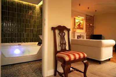 a bathroom with a tub and a chair next to a bath tub at WANNA SPA na Starym Mieście in Kraków