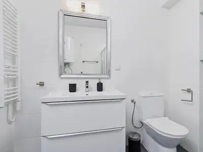 a white bathroom with a toilet and a mirror at Kazimierz- Warszauera 3 Street in Kraków