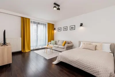 a white bedroom with a bed and a couch at Modern Apartments II with FREE underground parking in Kraków