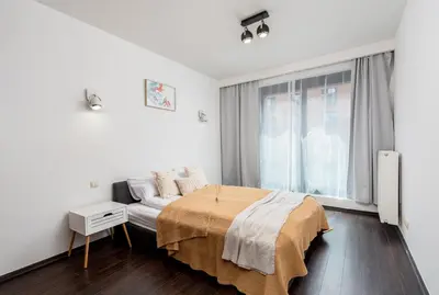 a white bedroom with a bed and a window at Modern Apartments II with FREE underground parking in Kraków