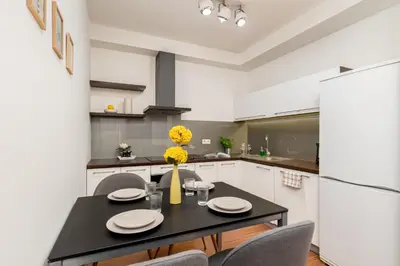a kitchen with a black table and chairs and a refrigerator at Modern Apartments II with FREE underground parking in Kraków
