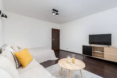 a white living room with a white couch and a tv at Modern Apartments II with FREE underground parking in Kraków