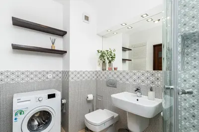 a bathroom with a washing machine and a sink at Modern Apartments II with FREE underground parking in Kraków