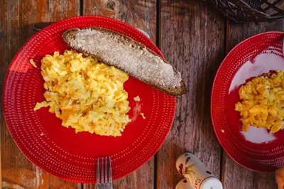 a red plate of food with a sausage and scrambled eggs at Chata pod Szczeblem in Lubień
