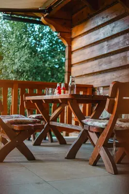 a wooden picnic table with two chairs on a porch at Chata pod Szczeblem in Lubień