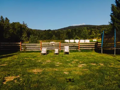 two chairs sitting in a field next to a fence at Chata pod Szczeblem in Lubień