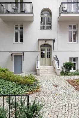 a white house with a green door and stairs at Apartment with balcony - Starowislna 41 in Kraków