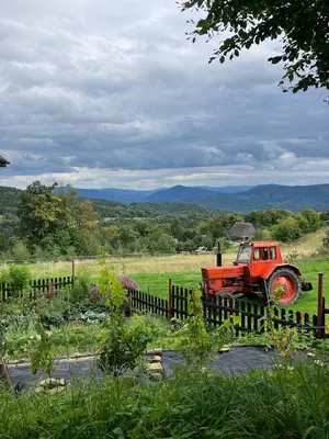 an orange truck parked in a field behind a fence at Chata Drapula - Gospodarstwo Agroturystyczne - Apartament na wyłączność z widokiem na góry i aneksem kuchennym in Zawadka