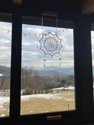 a window with a snowflake ornament hanging from it at Chata Drapula - Gospodarstwo Agroturystyczne - Apartament na wyłączność z widokiem na góry i aneksem kuchennym in Zawadka