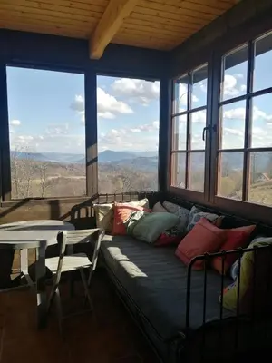 a living room with a couch and a table and windows at Chata Drapula - Gospodarstwo Agroturystyczne - Apartament na wyłączność z widokiem na góry i aneksem kuchennym in Zawadka
