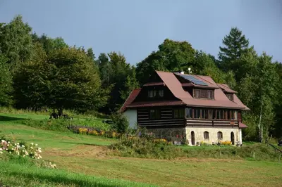 an old house with a roof on a field at Chata Drapula - Gospodarstwo Agroturystyczne - Apartament na wyłączność z widokiem na góry i aneksem kuchennym in Zawadka