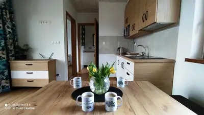 a kitchen with a wooden table with a vase of flowers at DOMEK W HORTENSJACH in Mucharz