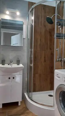 a bathroom with a shower and a sink and a washing machine at Good Apartament Skawina in Skawina