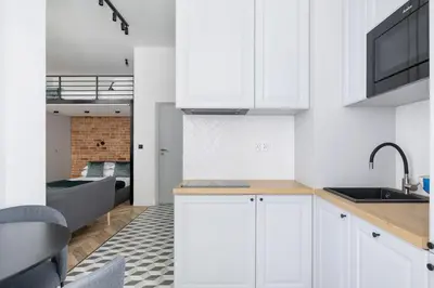 a kitchen with white cabinets and a sink and a couch at Balcony Apartment - Kazimierz- 41 Starowislna Street in Kraków