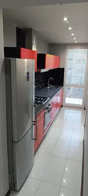 a kitchen with a stainless steel refrigerator and red cabinets at Apartament Olsza in Kraków