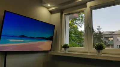 a flat screen tv in a room with two windows at Apartament Olsza in Kraków