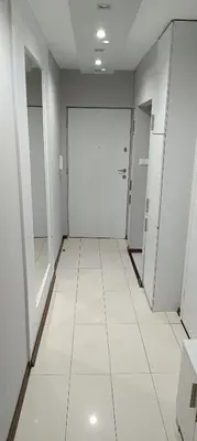 a hallway with white doors and white tile floors at Apartament Olsza in Kraków
